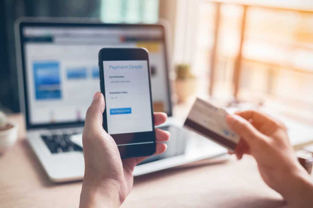 Man hands using smartphone and laptop computer for online shopping at home, Hand holding mobile phone with Payment Detail page display and credit card, online shopping concepts