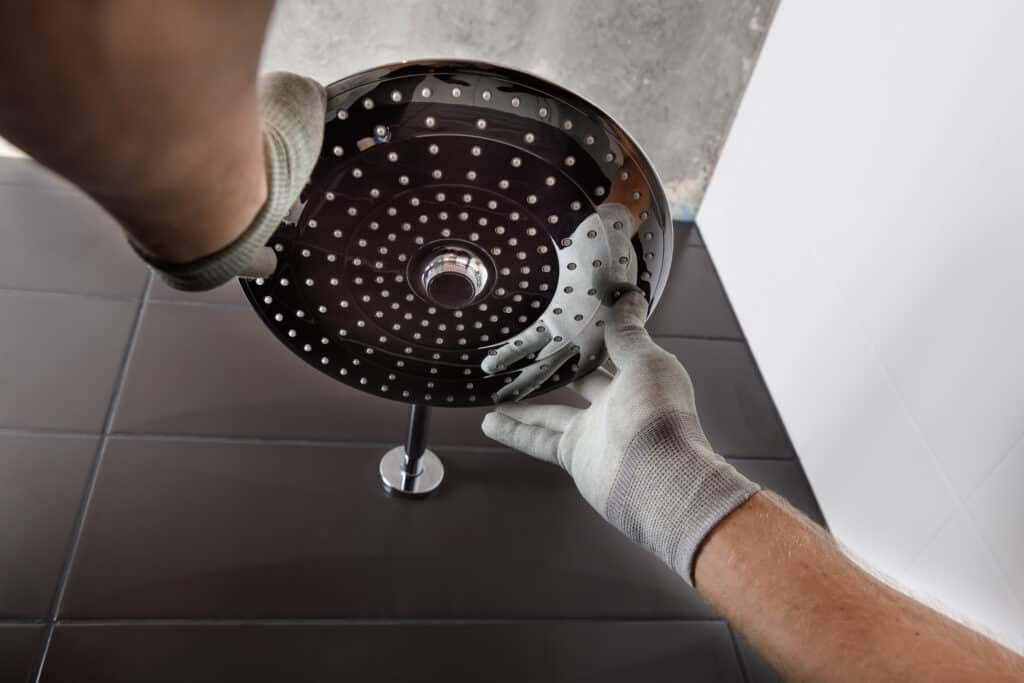 The worker's hands install the head of the built-in shower faucet.